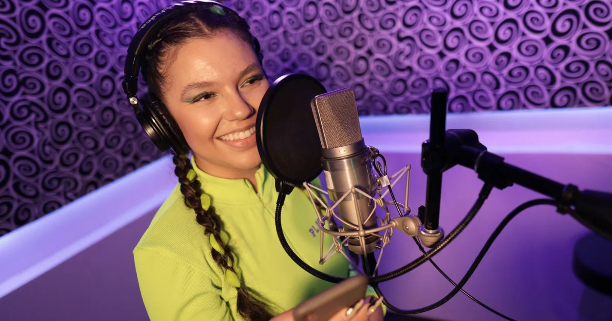 Voice talent reading copy from a phone at a condenser microphone with a pop filter in the MIX I booth, Los Angeles