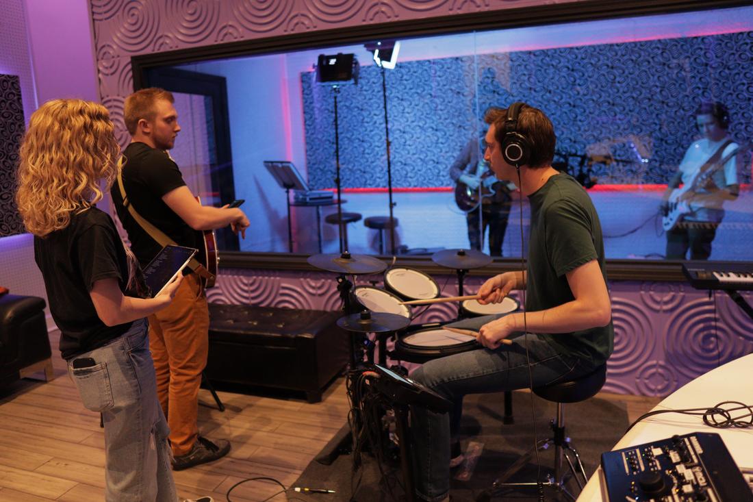 A band tracking live, drums and guitars, seen from the control room